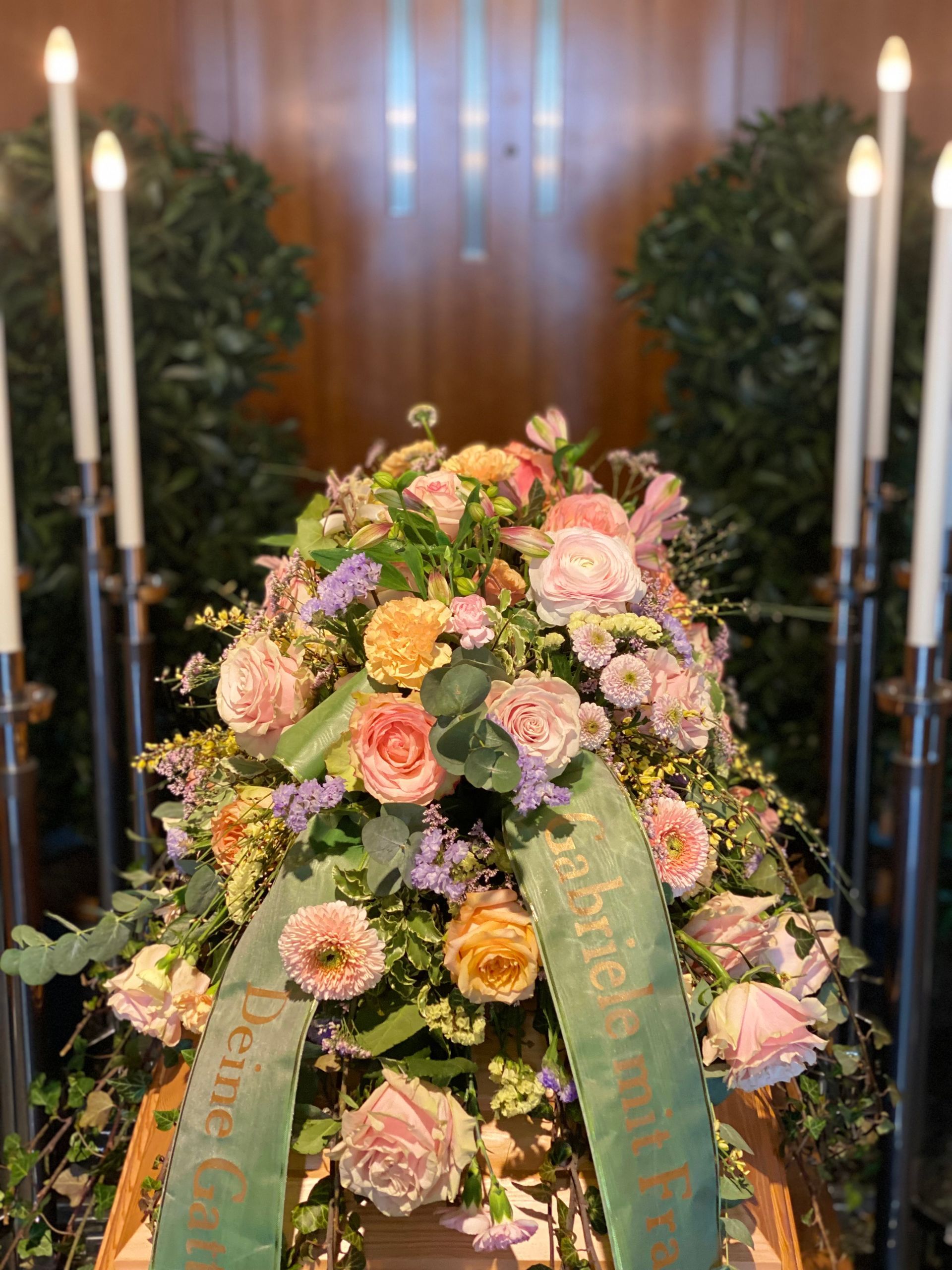 Ein mit Blumen und Kerzen geschmückter Sarg in einem Bestattungsinstitut.
