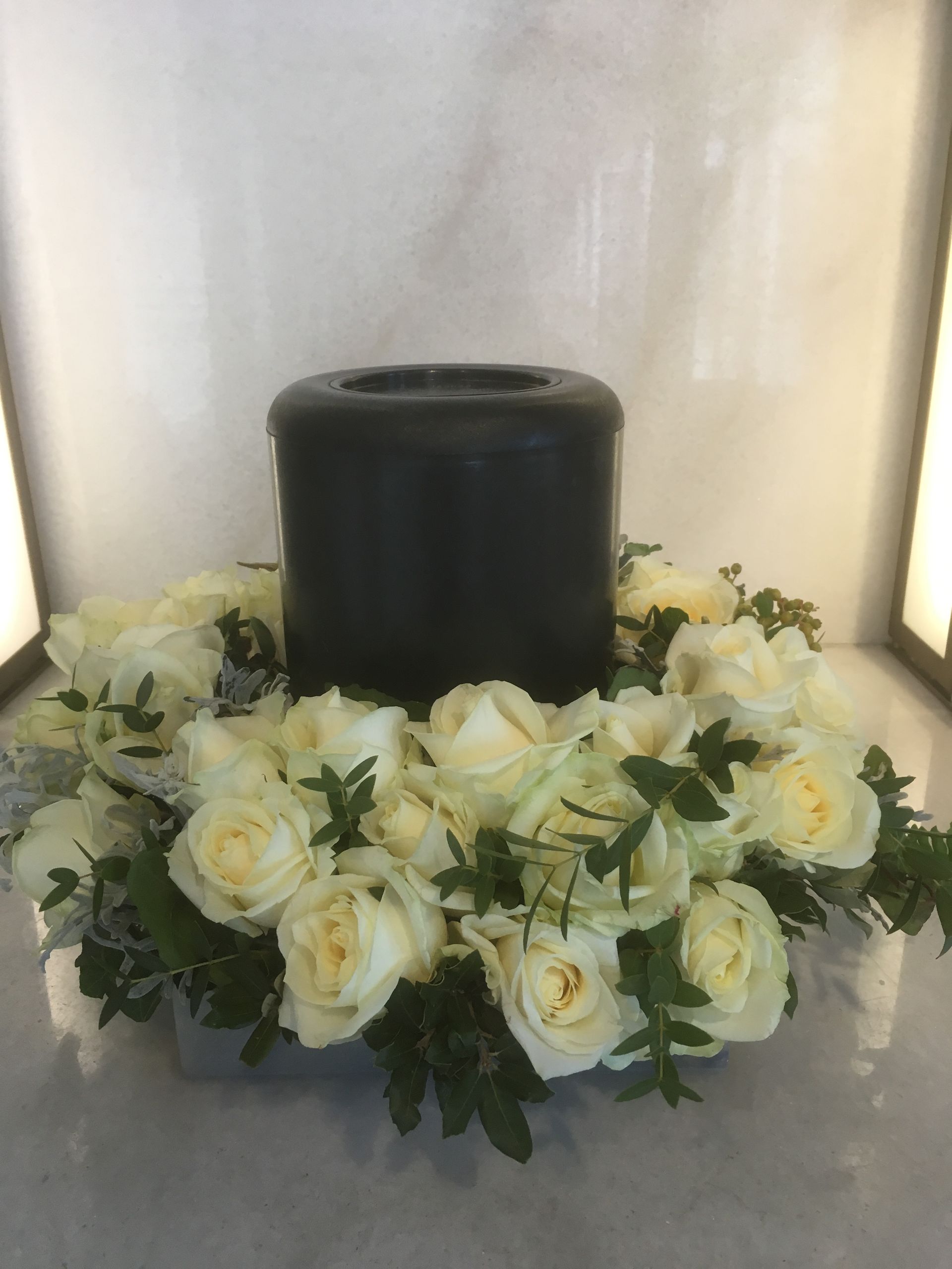 Eine Urne mit einem Herzen darauf ist von roten Rosen umgeben
