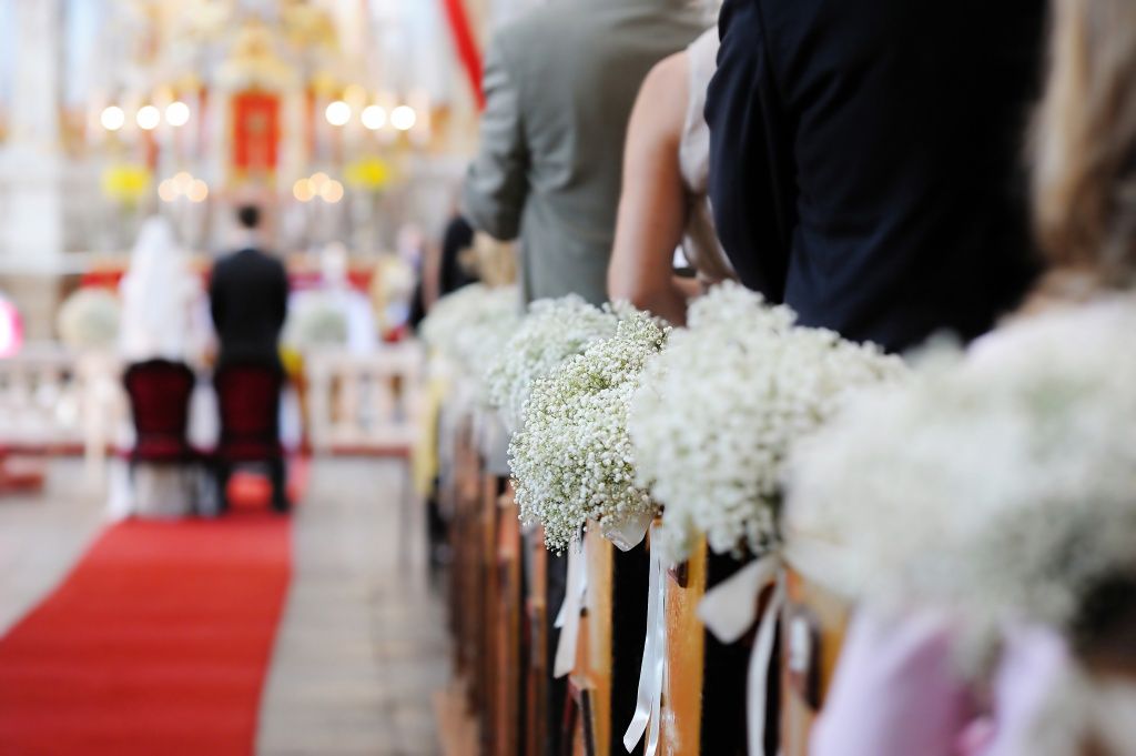 Eine Braut und ein Bräutigam sitzen während ihrer Hochzeitszeremonie in einer Kirche mit schöner Blumendekoration.