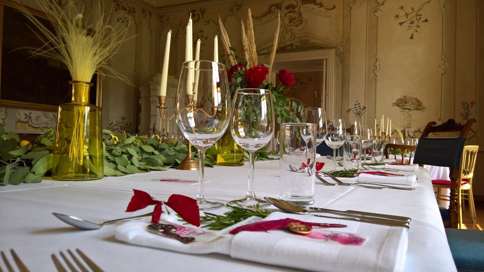 Ein langer Tisch ist für eine Dinnerparty mit Weingläsern und Kerzen gedeckt.