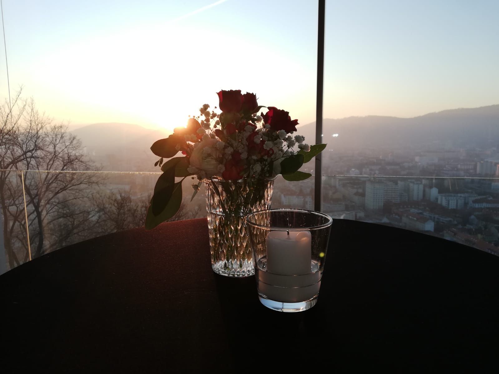 Ein Tisch mit einer Vase mit Blumen und einer Kerze darauf