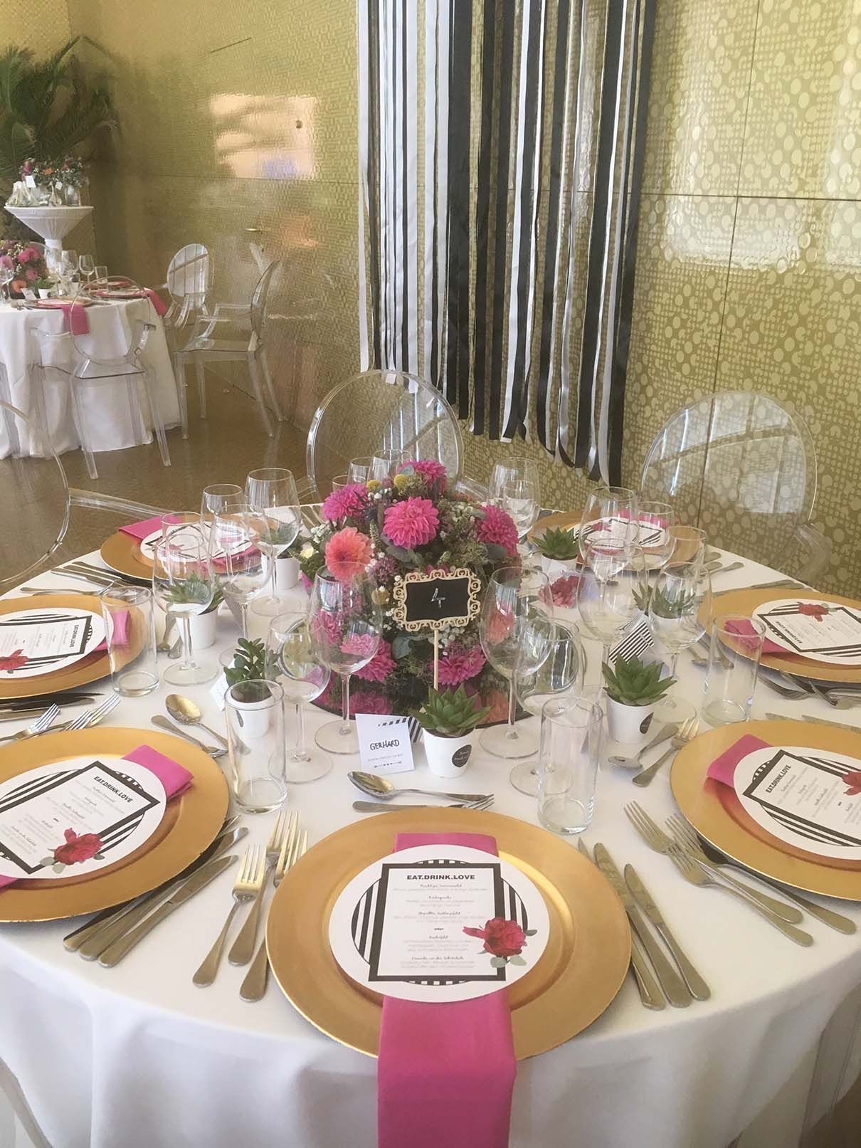 Ein für einen Hochzeitsempfang gedeckter Tisch mit Tellern, Besteck und Blumen.