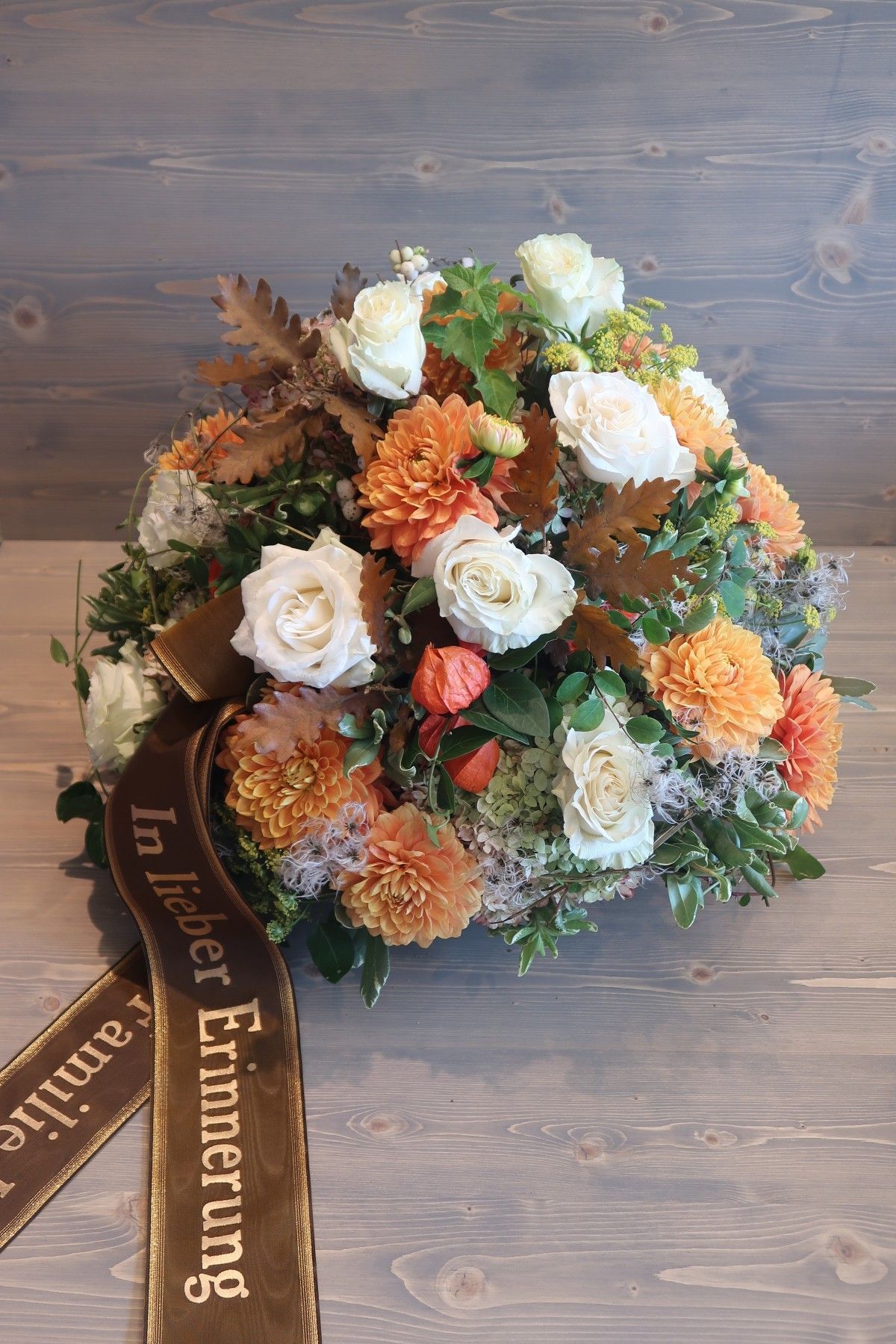 Ein rund gestecktes Gesteck aus herbstlichen Blüten in weiß und orange Tönen.