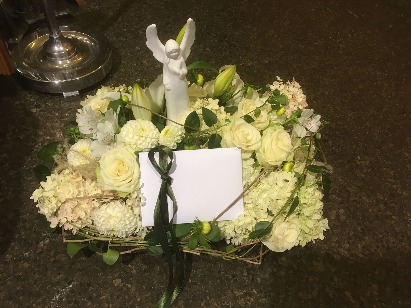 Ein weißer Engel sitzt auf einem weißen Blumenarrangement