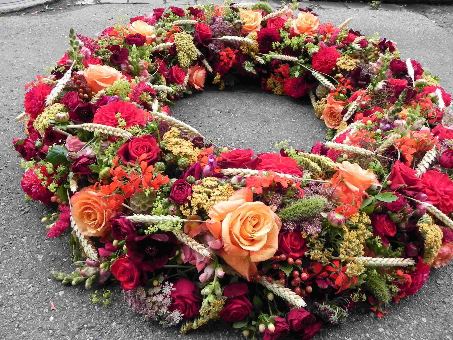 Auf dem Boden liegt ein großer rot gruener Blumenkranz.
