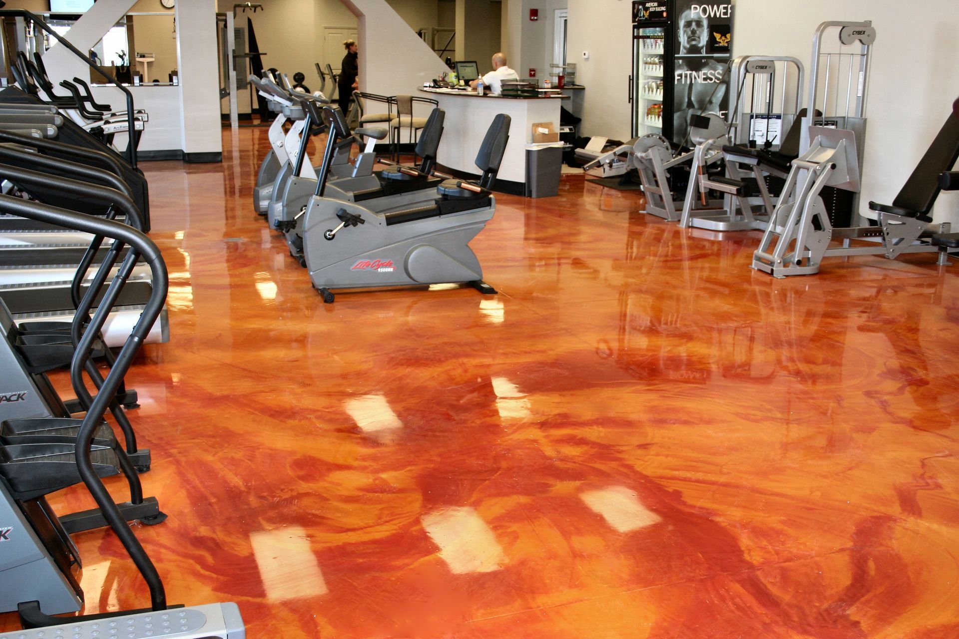 A gym with a lot of exercise equipment on a shiny concrete floor.