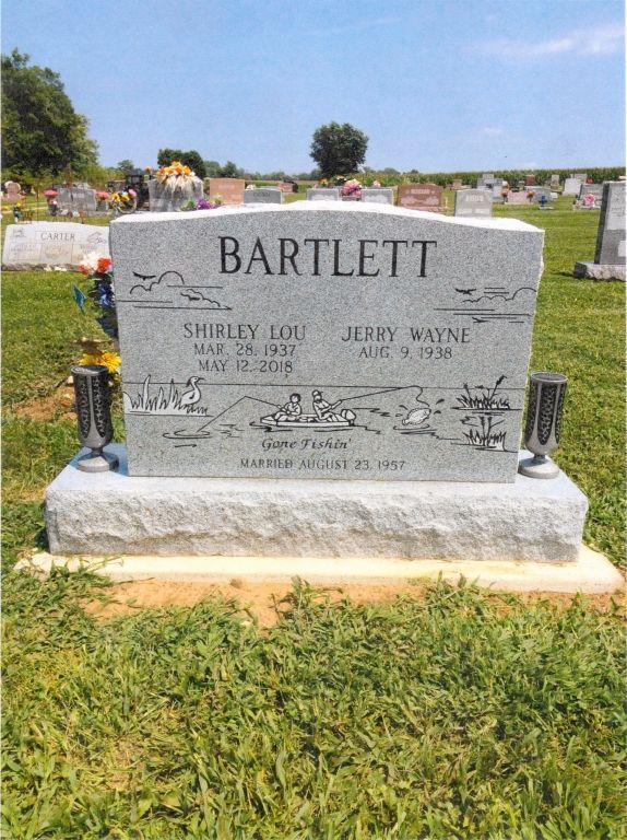 Family gravestone in a cemetery with engraved names and floral decorations.