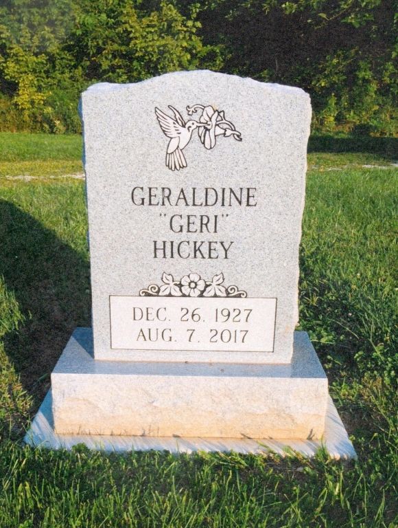 White gravestone in a grassy cemetery with an angel engraving