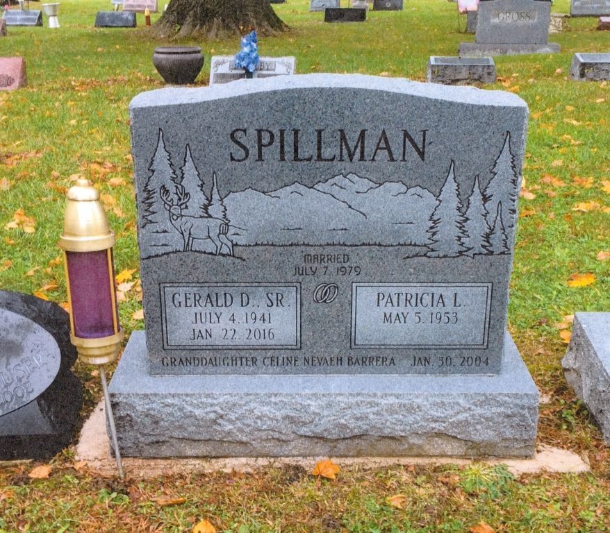 Gray gravestone in a cemetery with two memorial plaques