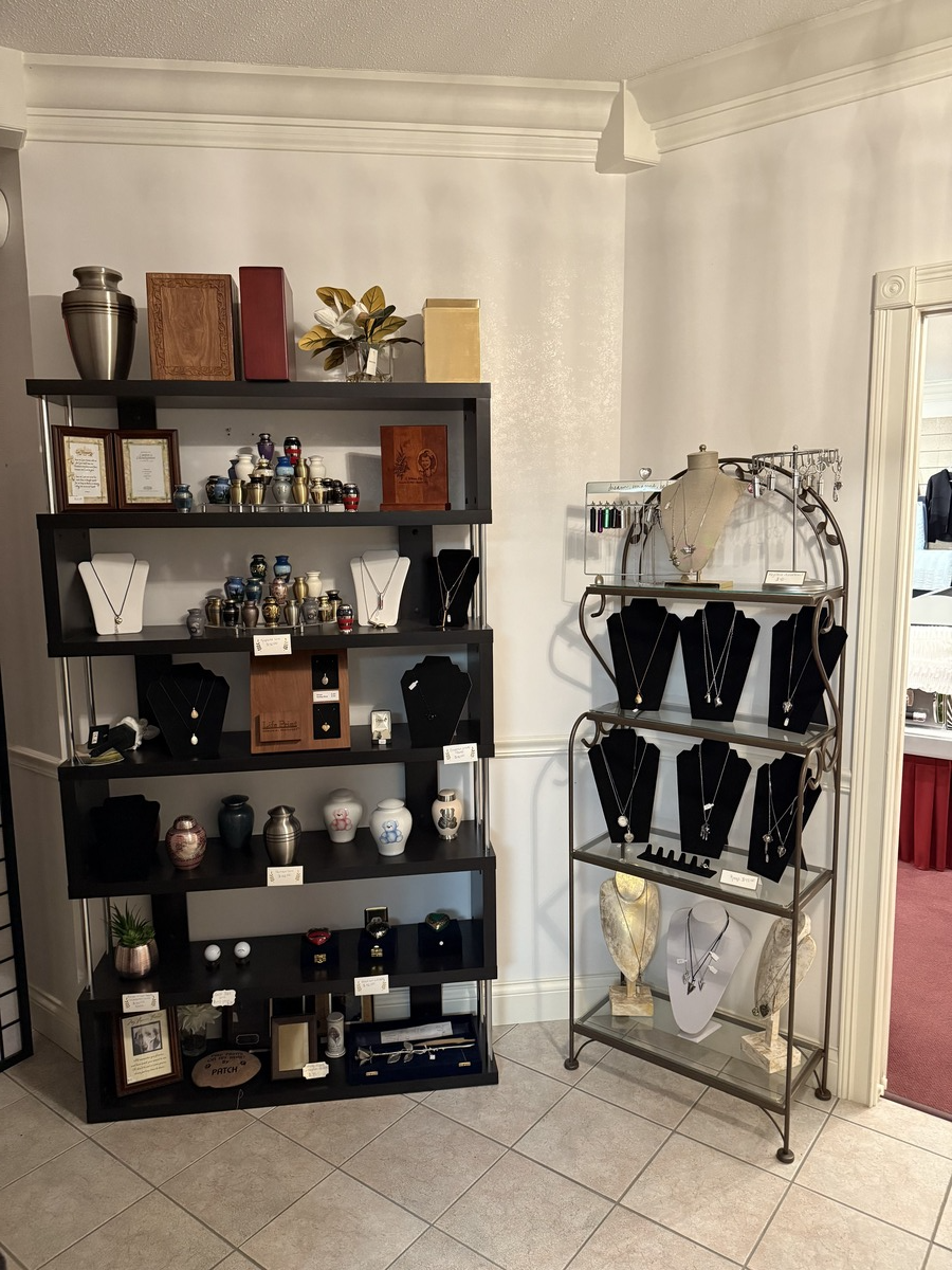 Black shelving and a white metal rack holding decor and mannequin jewelry displays in a tiled room