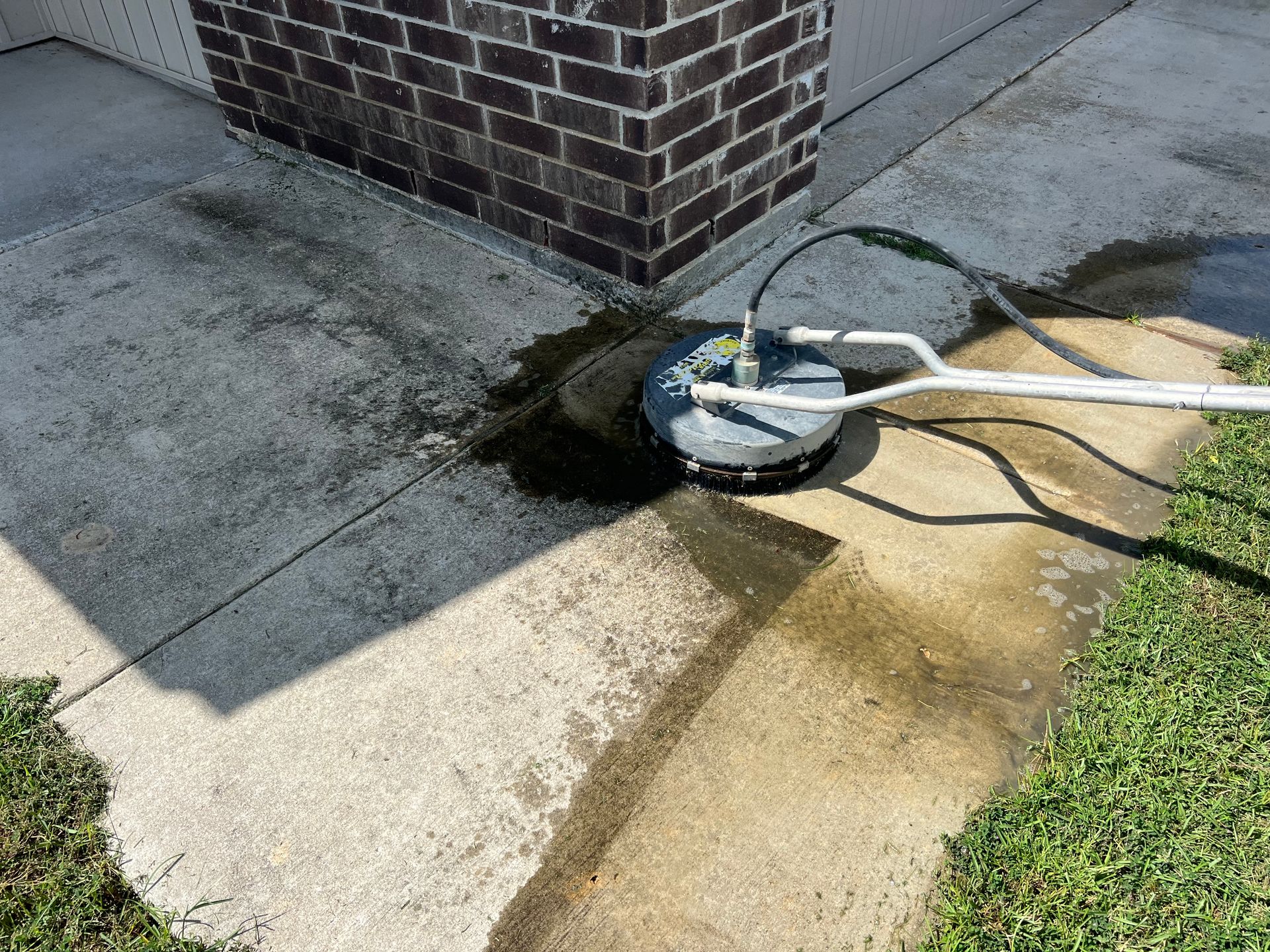 A concrete sidewalk is being cleaned with a pressure washer.