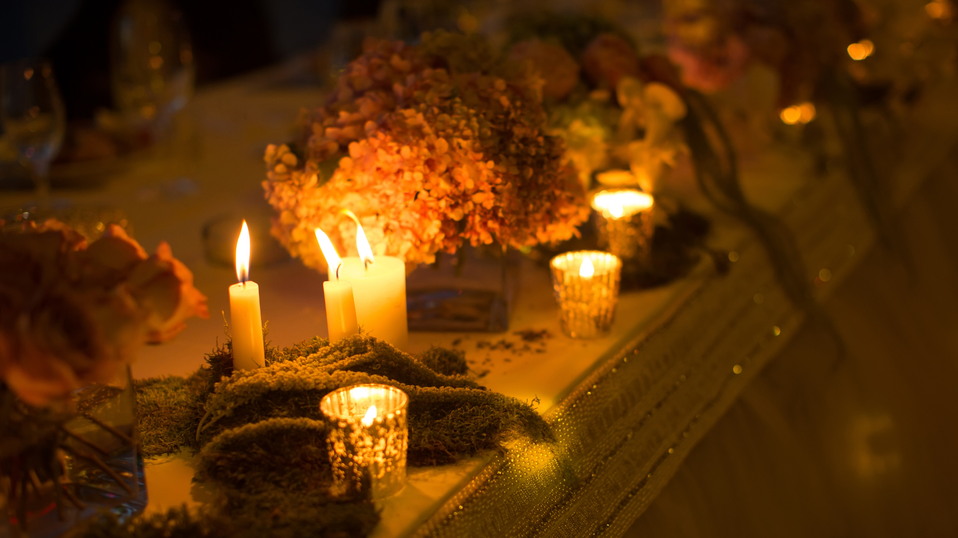 Candlelit table with floral centerpiece, soft lighting, and decorative candles.
