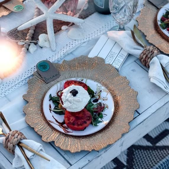 Overhead view of a dining table with seafood salad on a plate, gold charger, and a starfish.