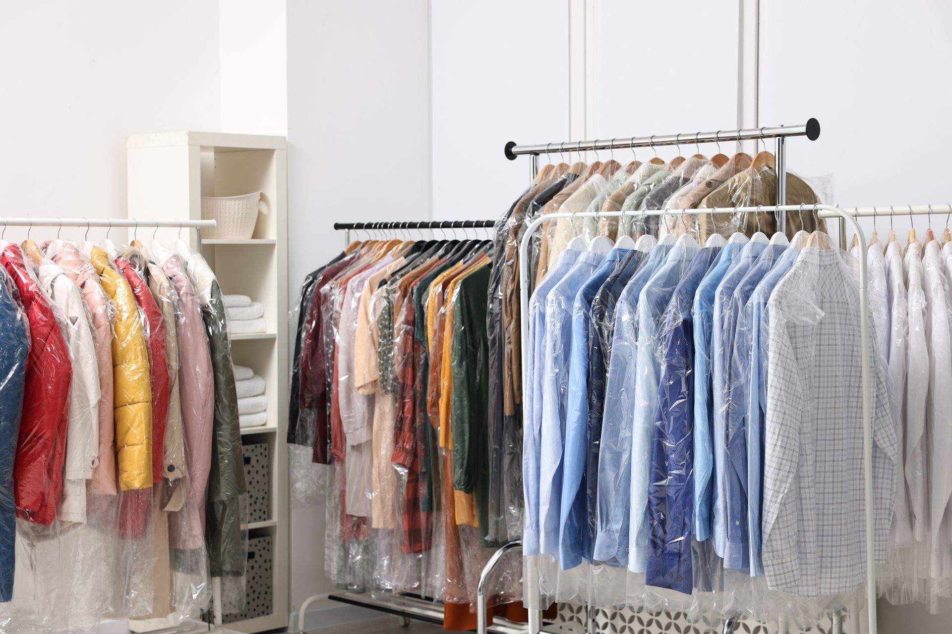 Clothing racks filled with garments in protective plastic at a dry cleaner. Clothing racks filled with garments in protective plastic at a dry cleaner.