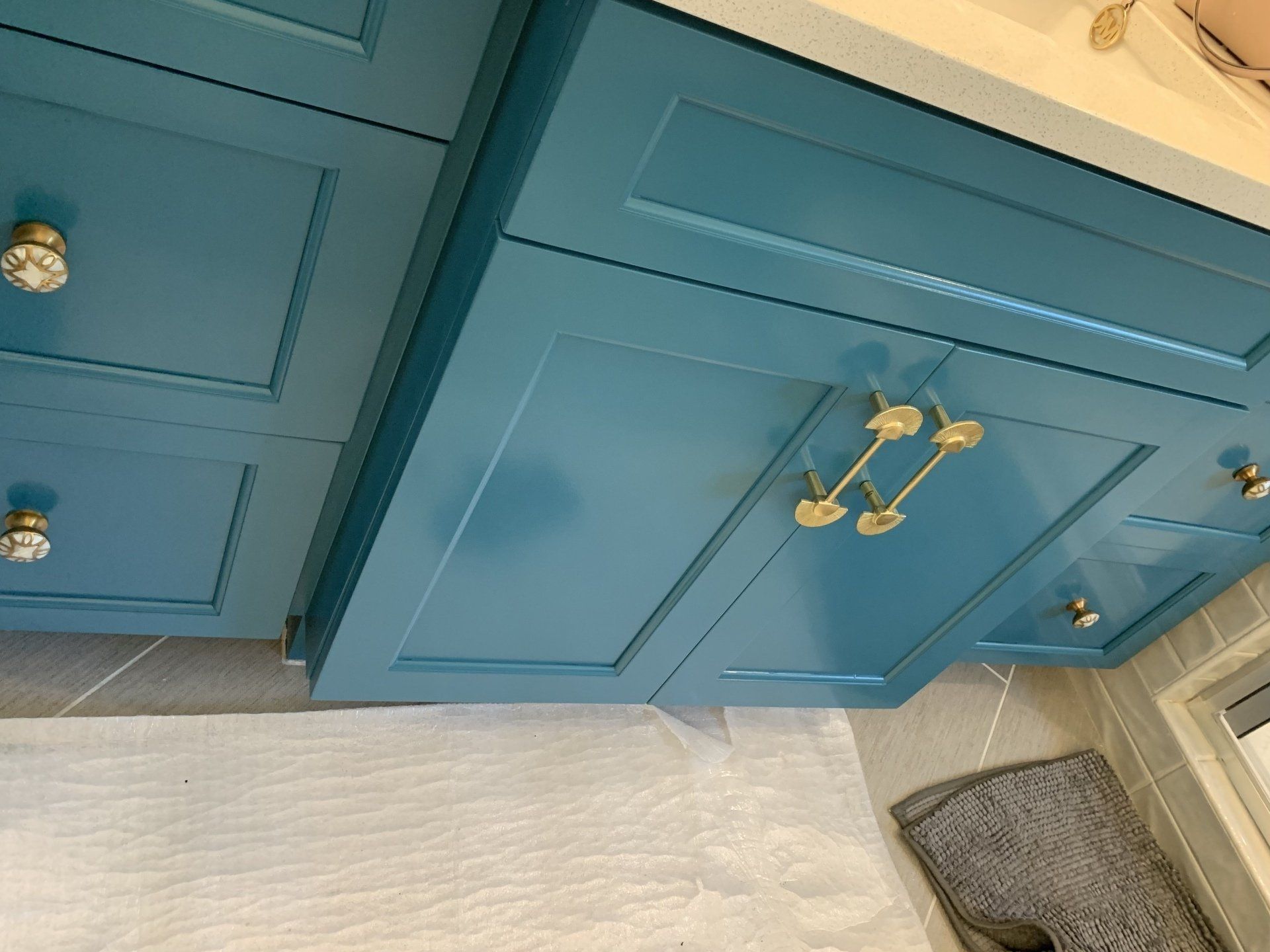 A bathroom vanity with blue cabinets and gold handles