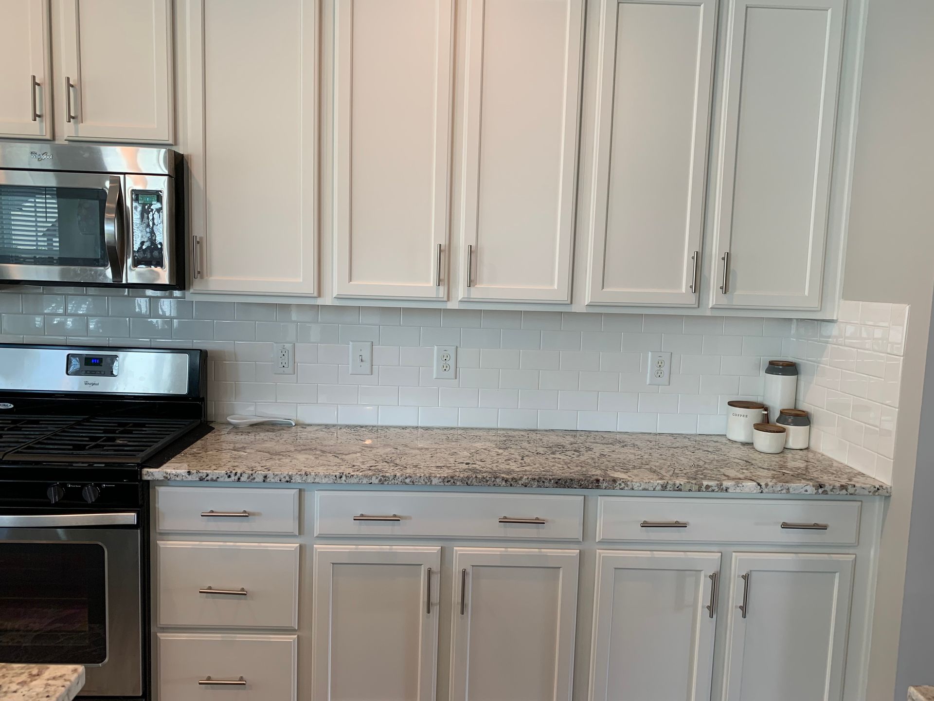 A kitchen with white cabinets and granite counter tops