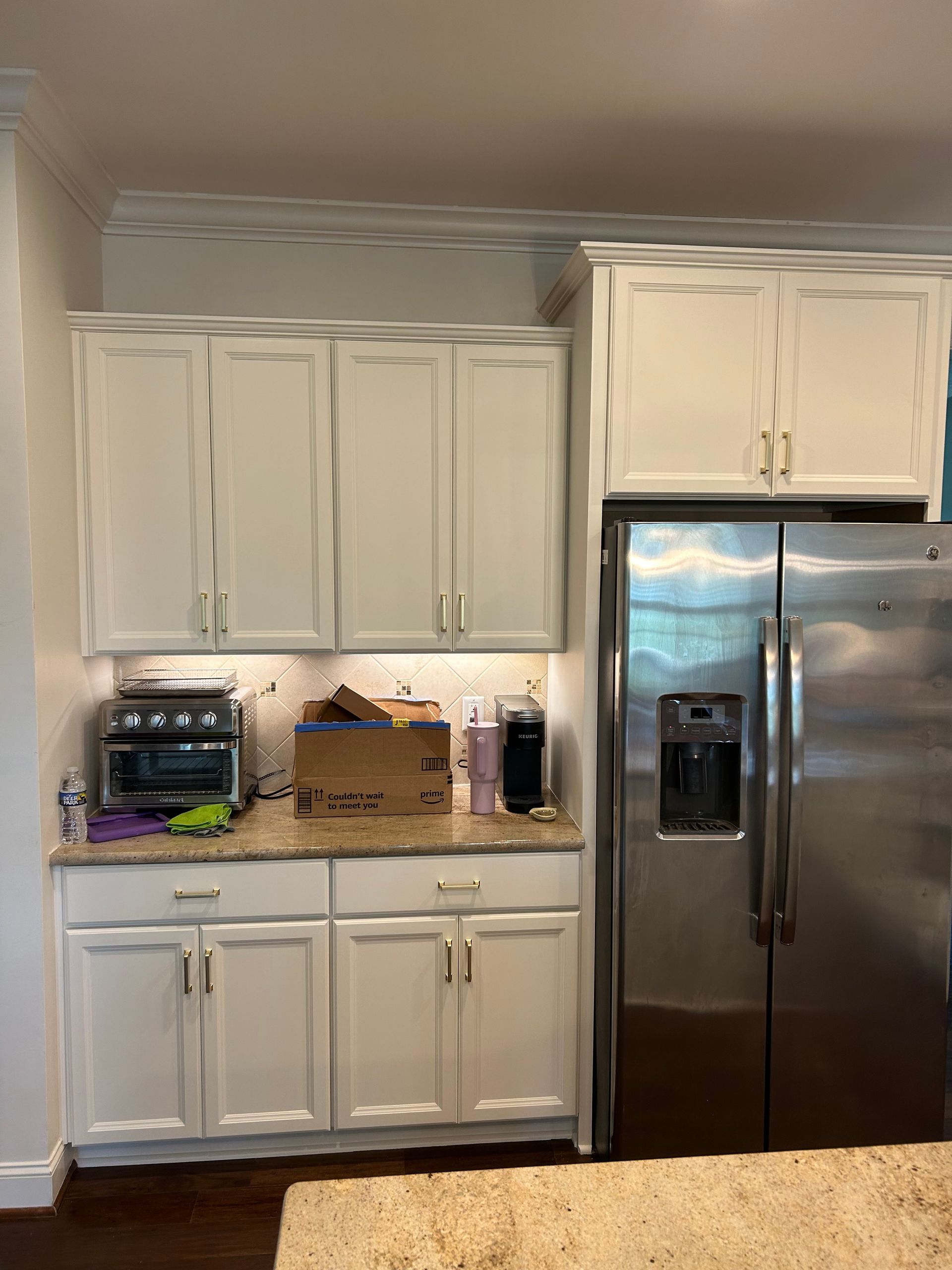 A kitchen with white cabinets and a stainless steel refrigerator.