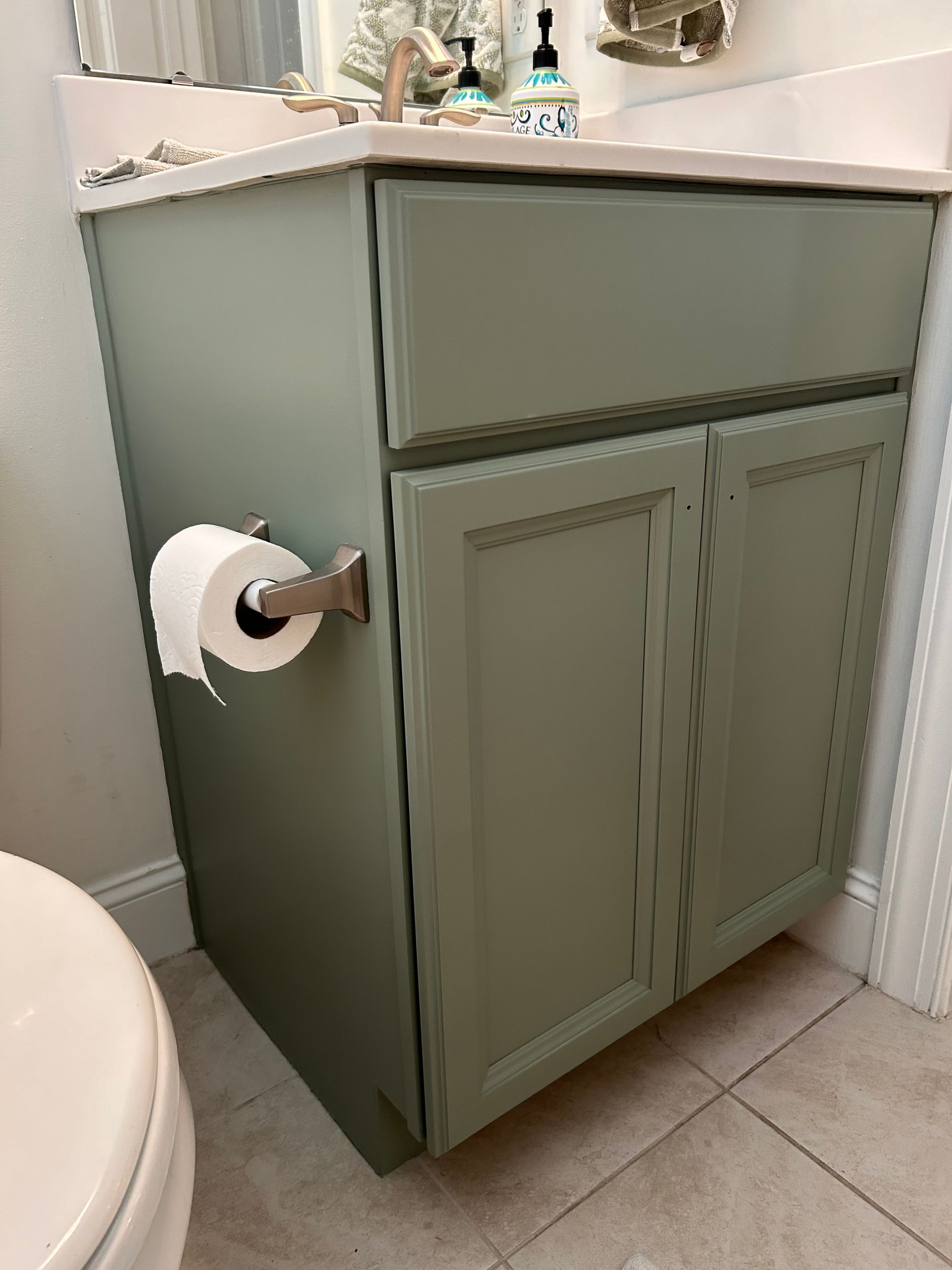A bathroom vanity with a toilet and a paper towel holder.