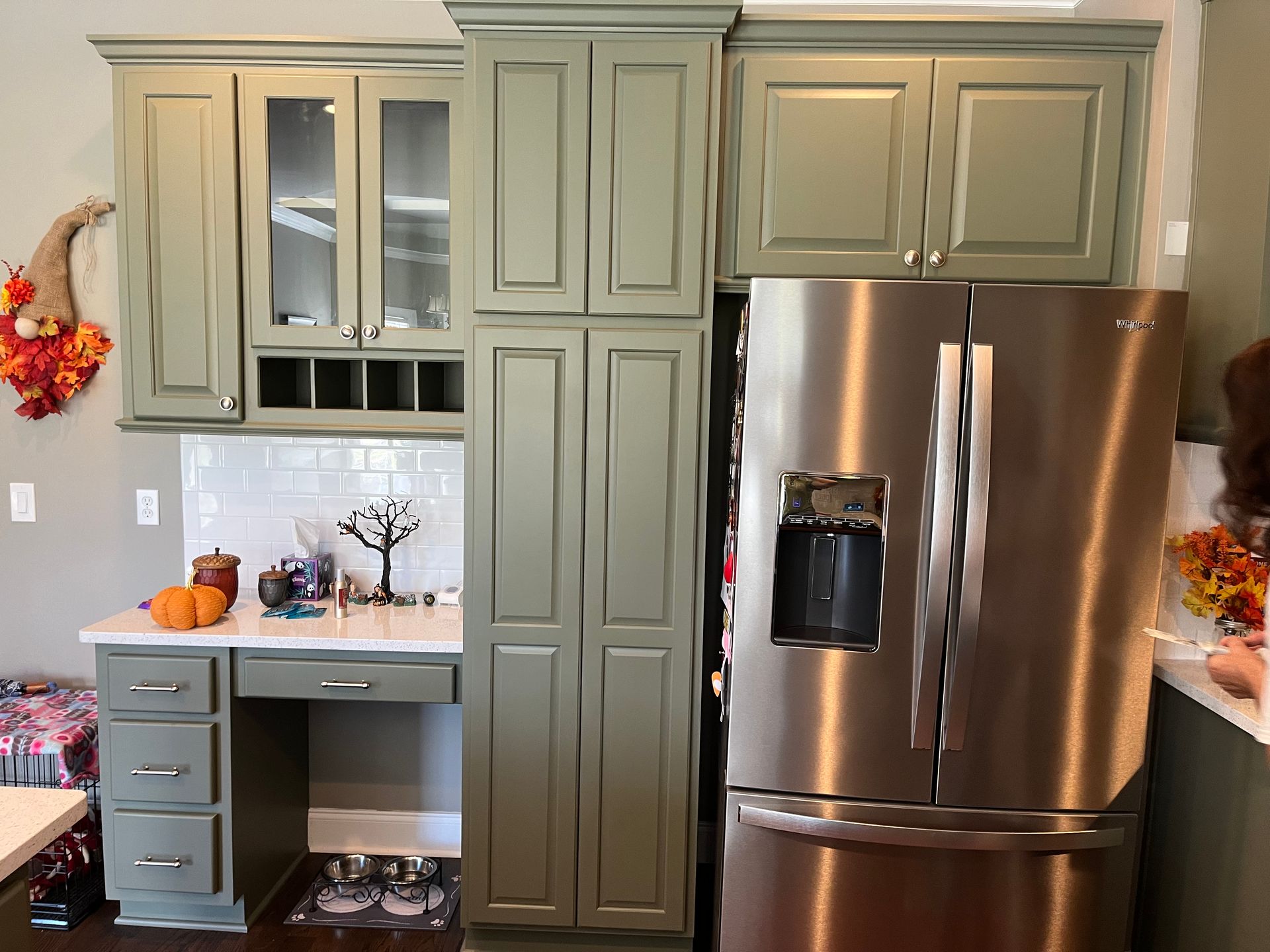 A kitchen with green cabinets and a stainless steel refrigerator.