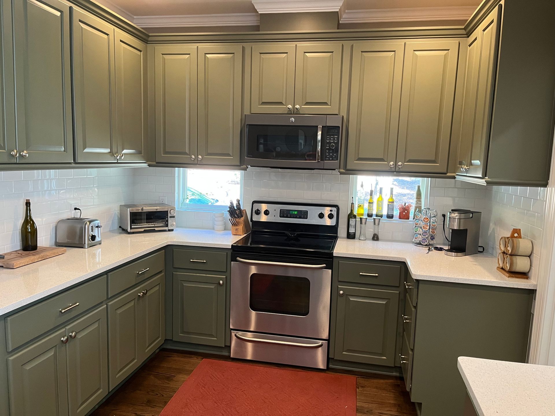 A kitchen with stainless steel appliances and green cabinets