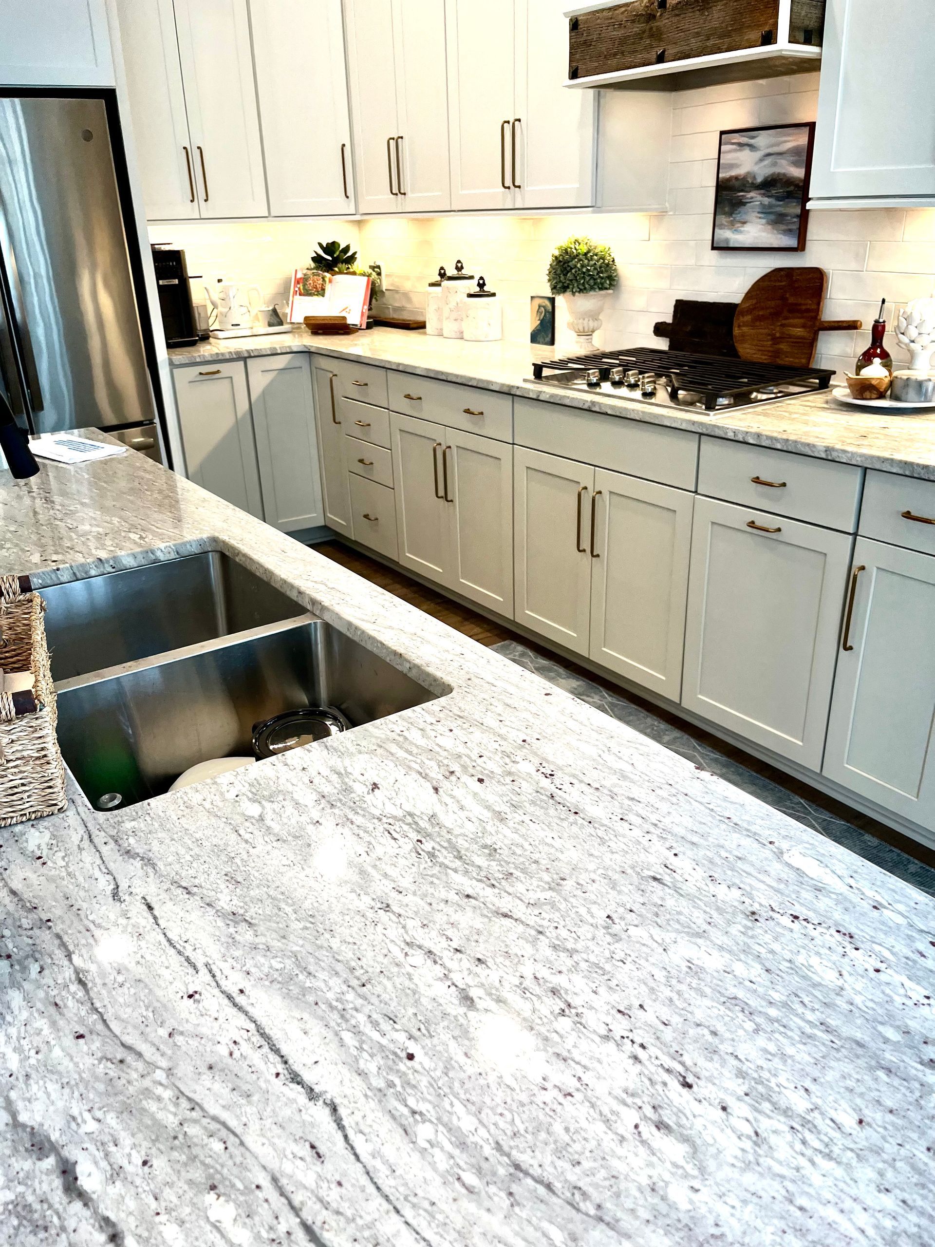 A kitchen with white cabinets , stainless steel appliances , and granite counter tops.