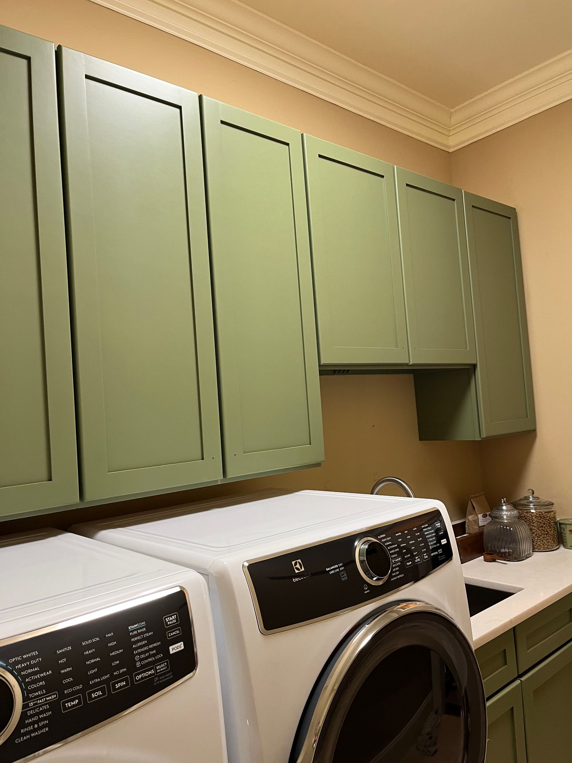 A laundry room with green cabinets and a washer and dryer