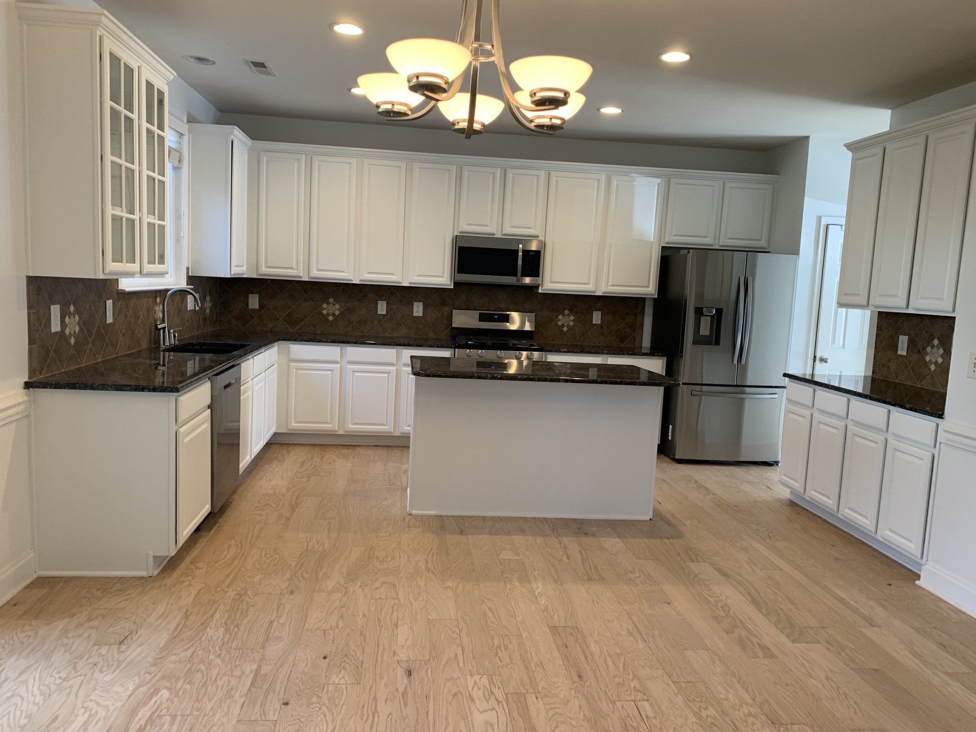 A large kitchen with white cabinets and stainless steel appliances