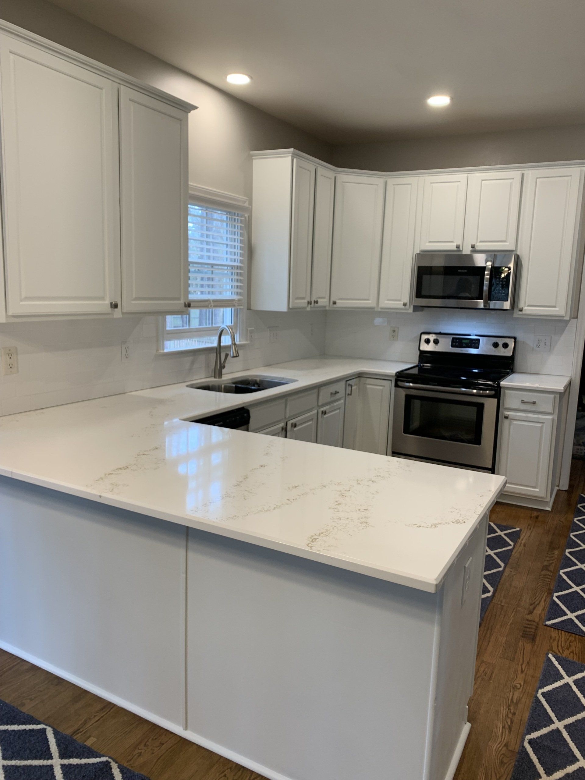 A kitchen with white cabinets , stainless steel appliances , and a large island.