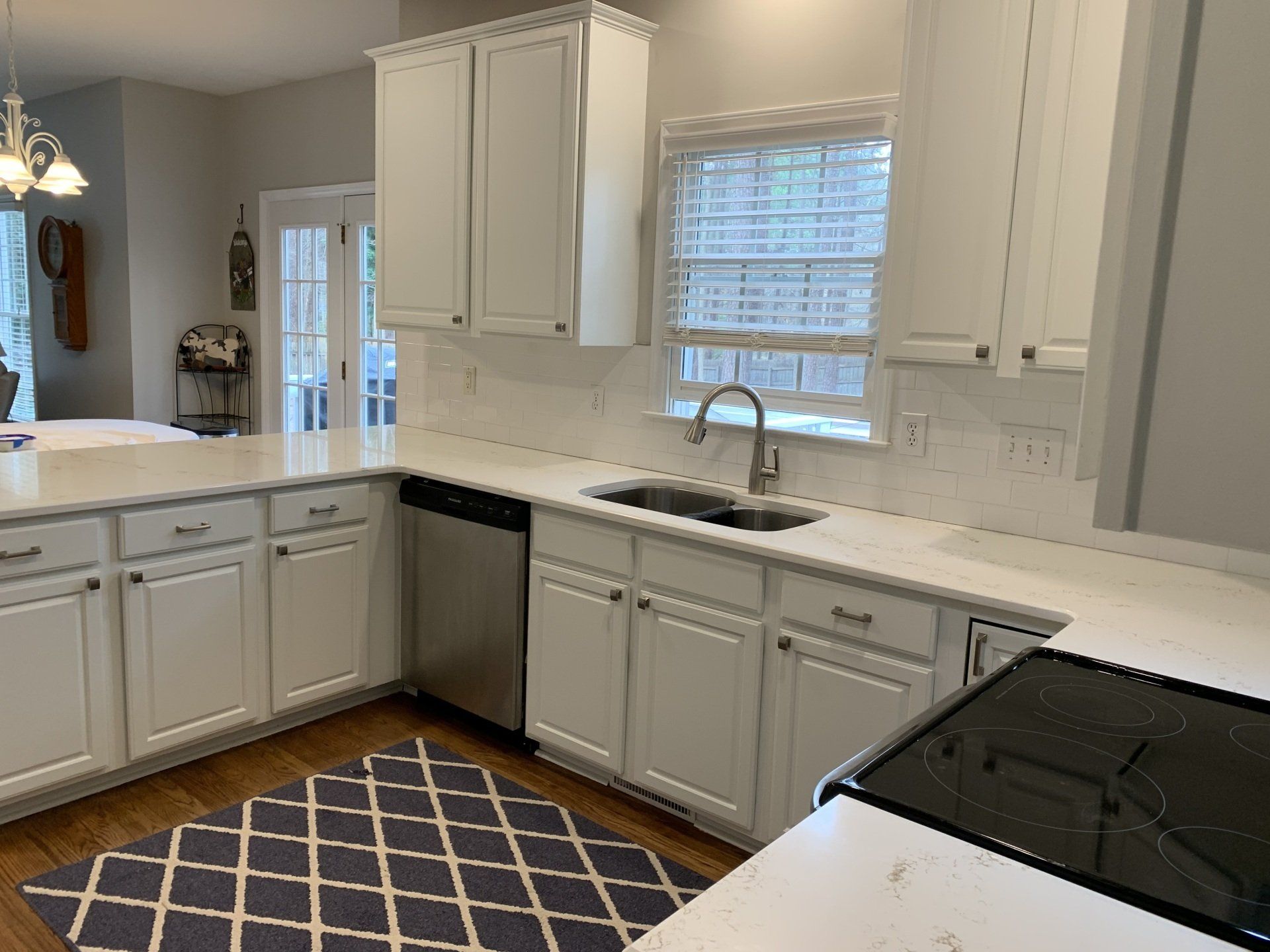 A kitchen with white cabinets , stainless steel appliances , a sink and a window.