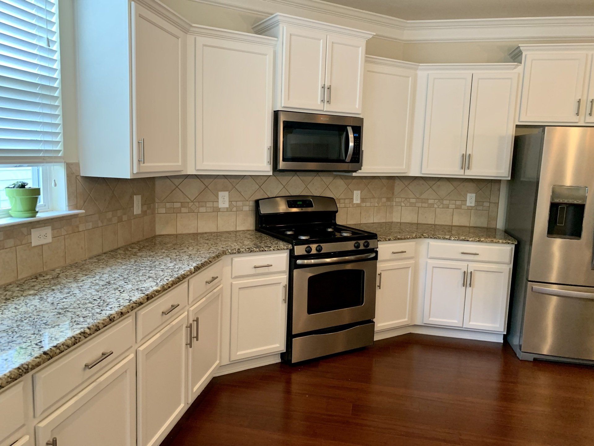 A kitchen with white cabinets stainless steel appliances and granite counter tops