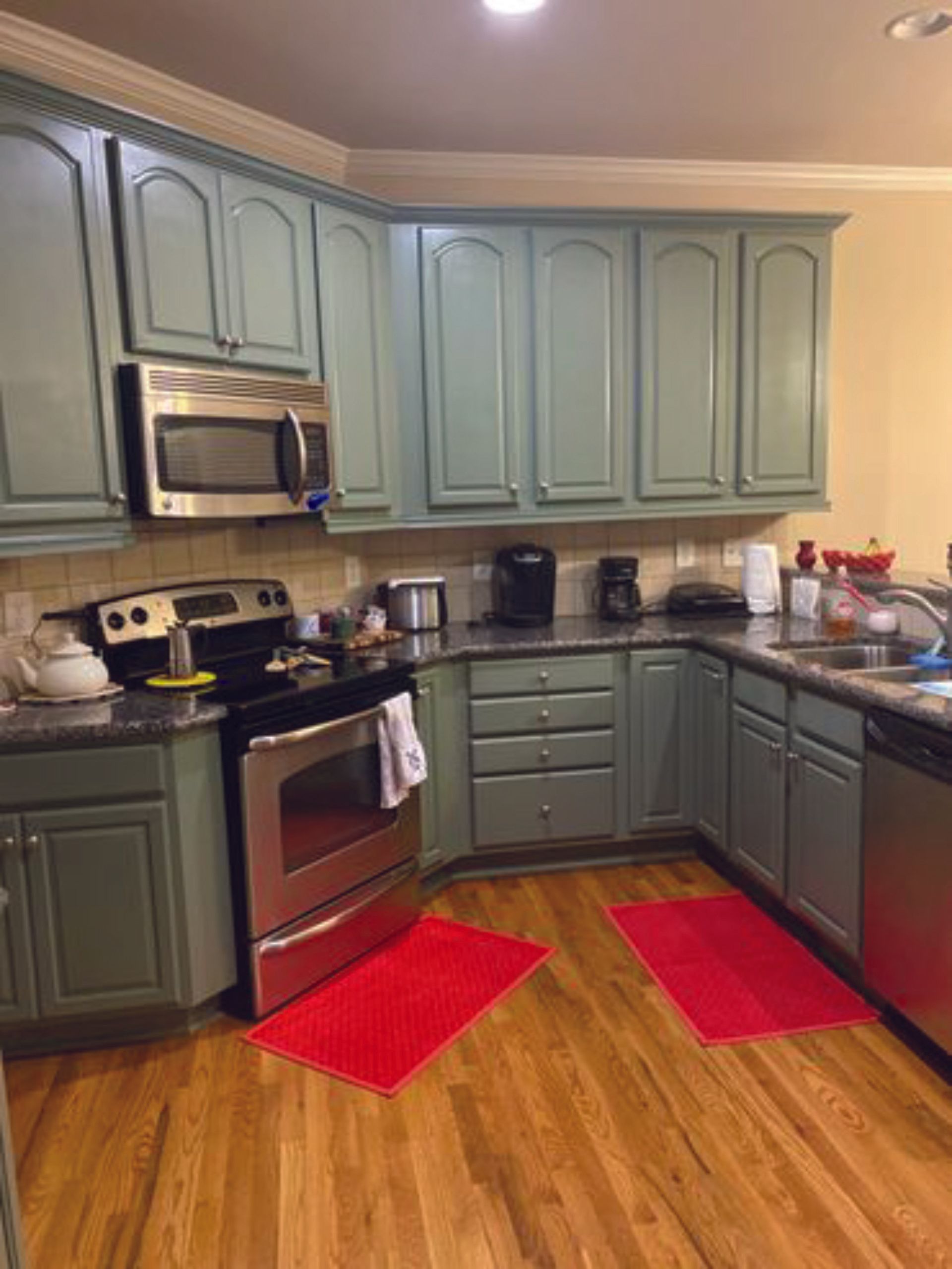 A kitchen with green cabinets and stainless steel appliances.