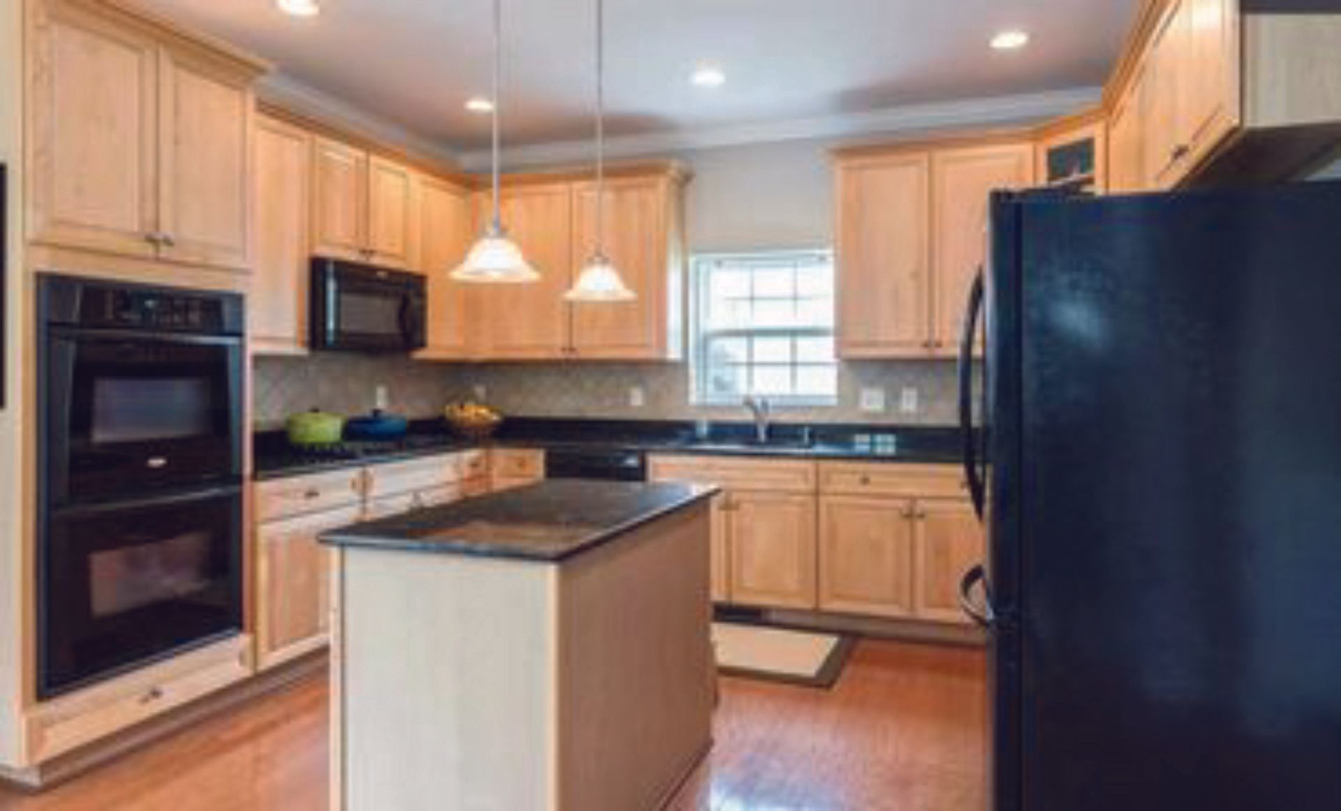 A kitchen with wooden cabinets and a black refrigerator.