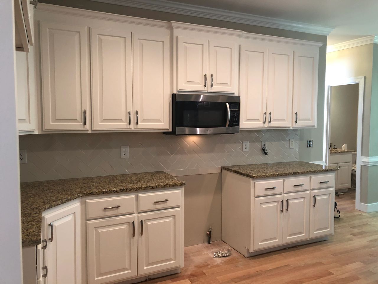 A kitchen with white cabinets and granite counter tops.