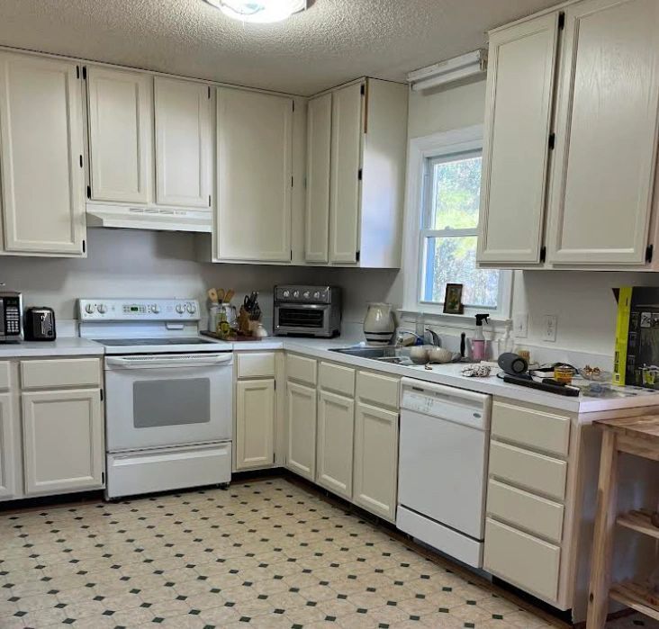 A kitchen with white cabinets , a stove and a dishwasher