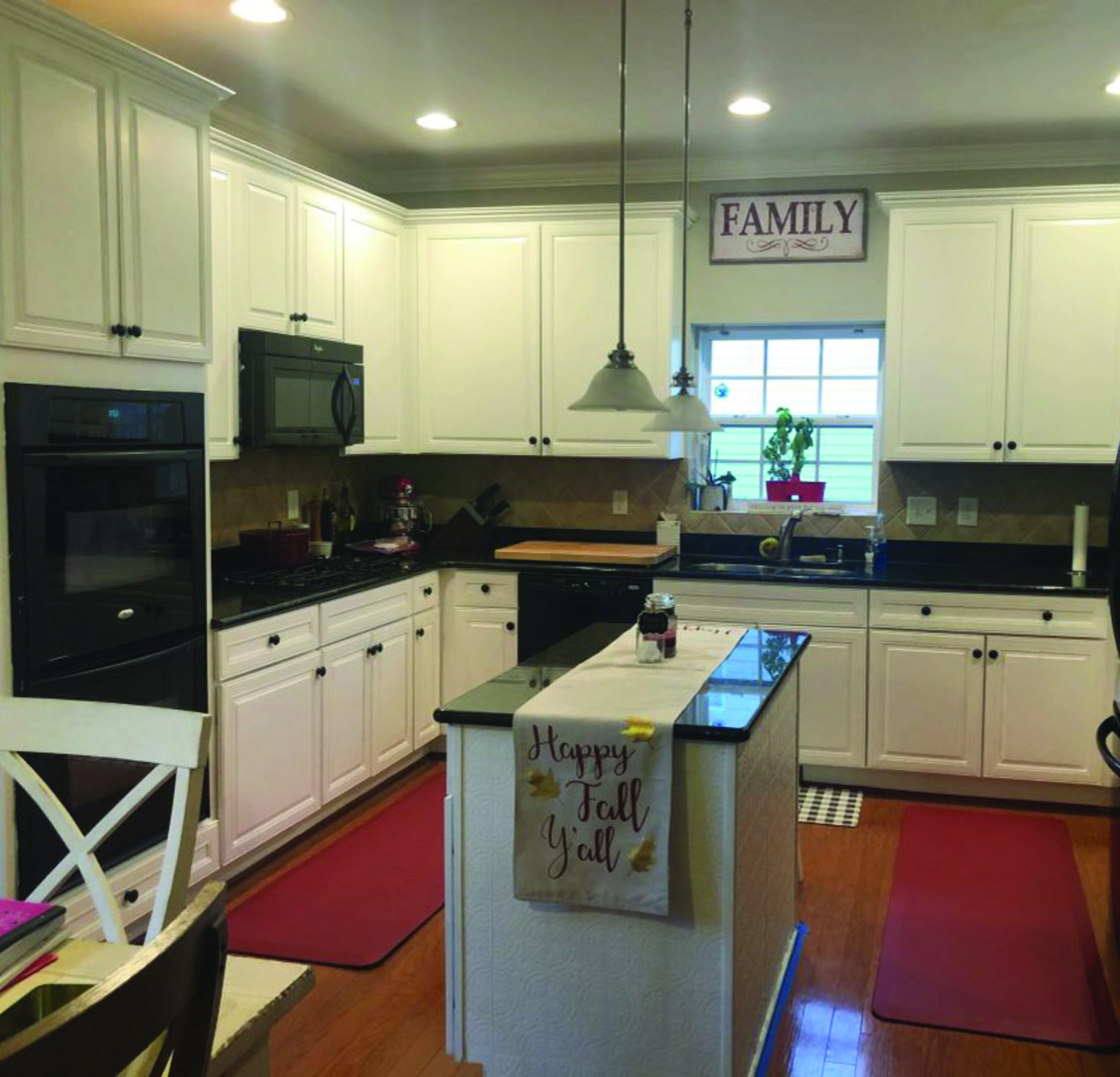 A kitchen with white cabinets and a sign that says family