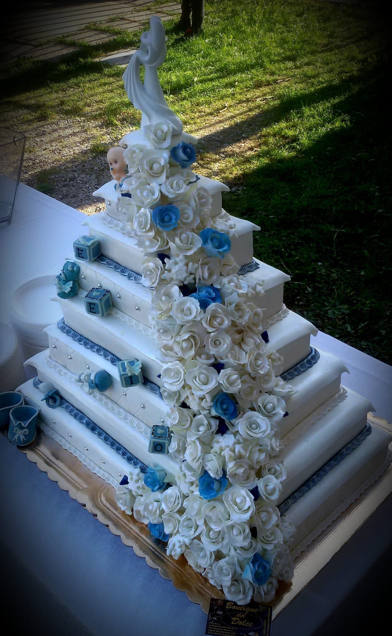 Una torta nuziale bianca con fiori blu e un cigno in cima