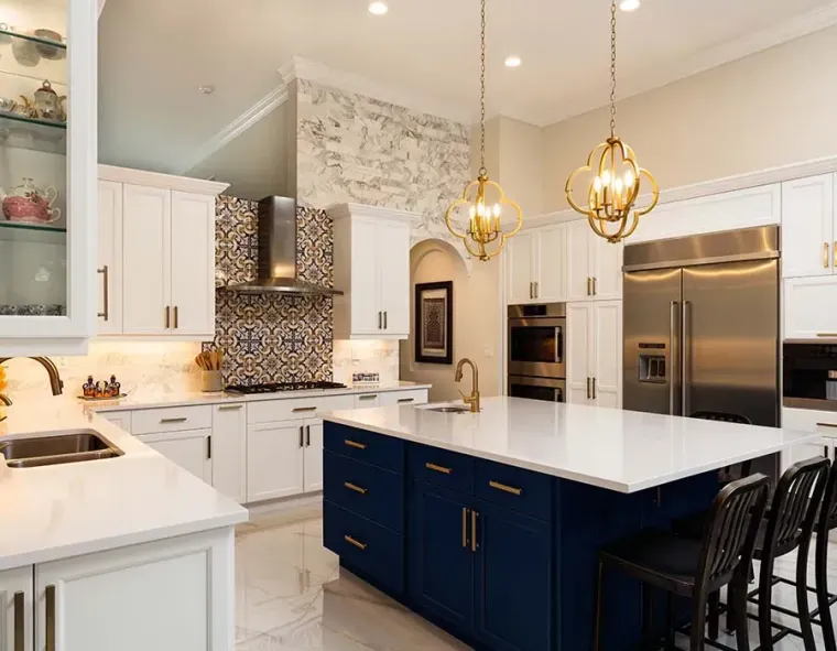 Bright modern kitchen with navy island, white cabinets, gold pendants, and stainless steel appliances