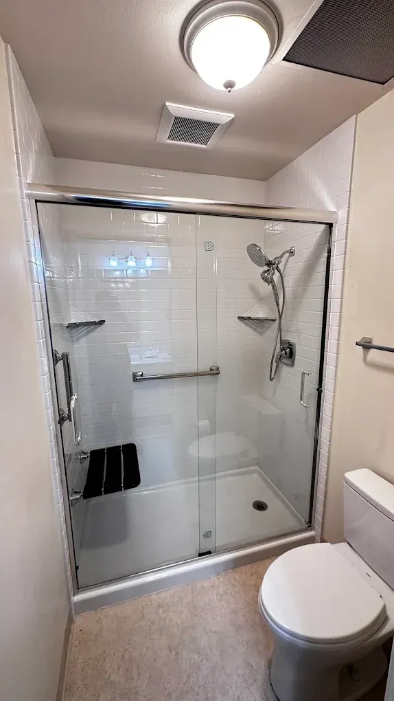 Small bathroom with glass shower enclosure, toilet, and ceiling light.