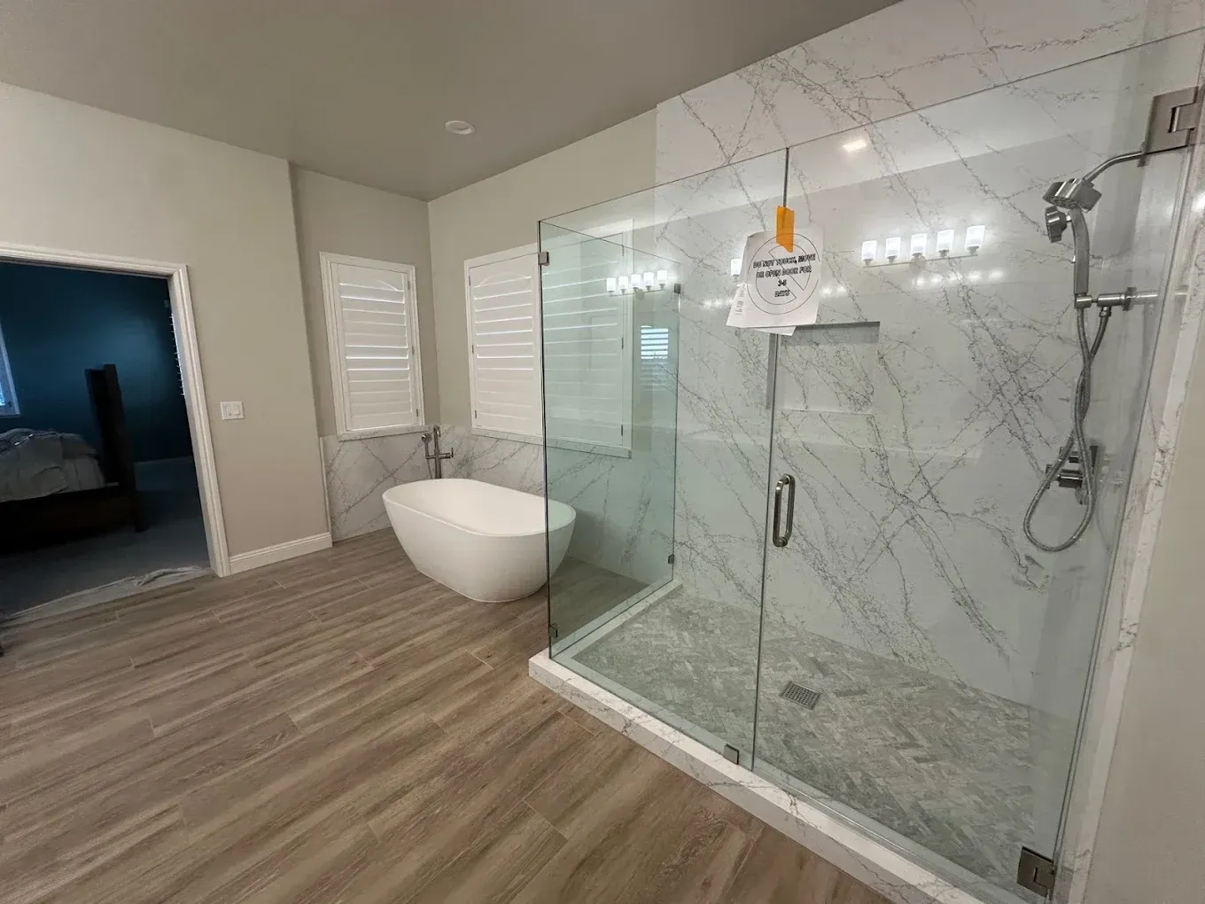 Modern bathroom with glass shower, freestanding tub, and light wood flooring