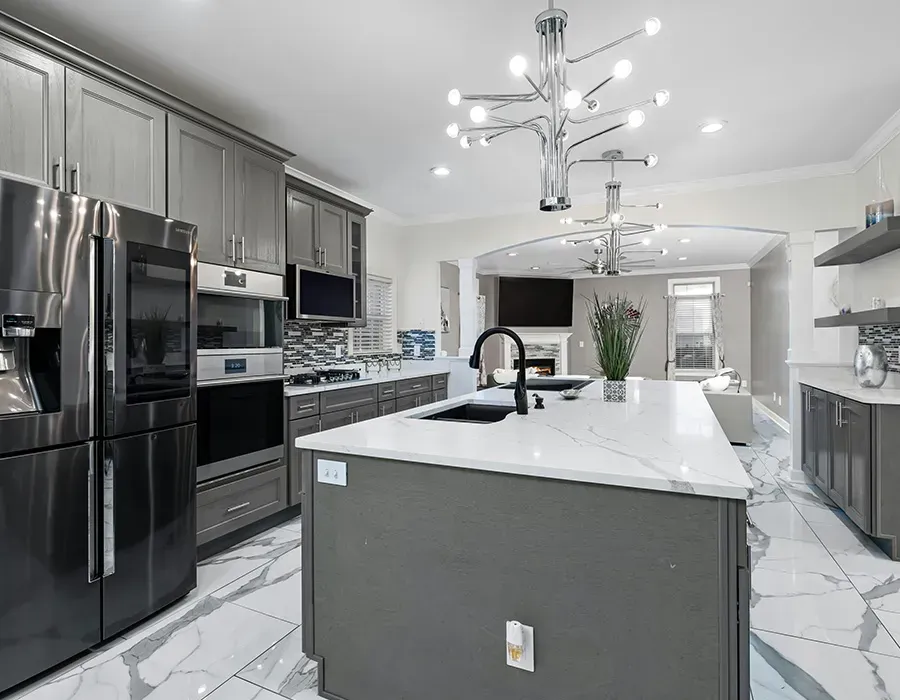 Modern gray kitchen with marble island, stainless steel appliances, pendant light, and white tiled floor