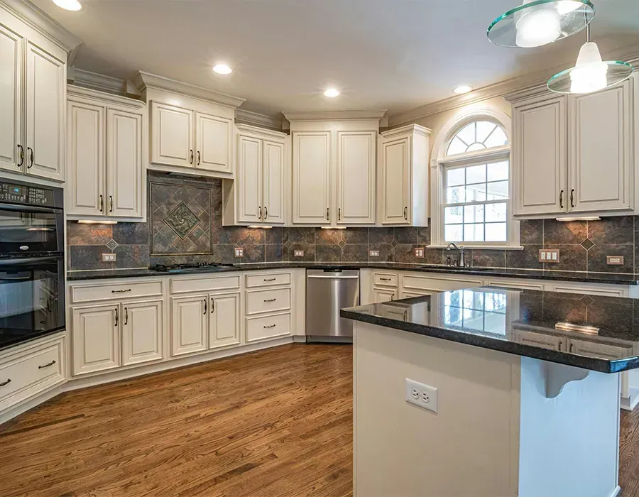 Bright modern kitchen with cream cabinets, dark countertops, hardwood floors, and a center island.