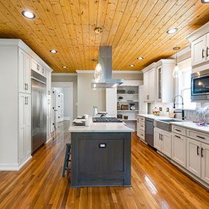 Modern kitchen with white cabinets, wood ceiling, central island, and stainless steel appliances