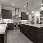 Modern kitchen with dark wood cabinets, granite island, stainless steel appliances, and pendant lights.