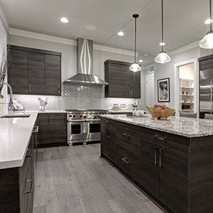 Modern kitchen with dark wood cabinets, granite island, stainless steel appliances, and pendant lights.