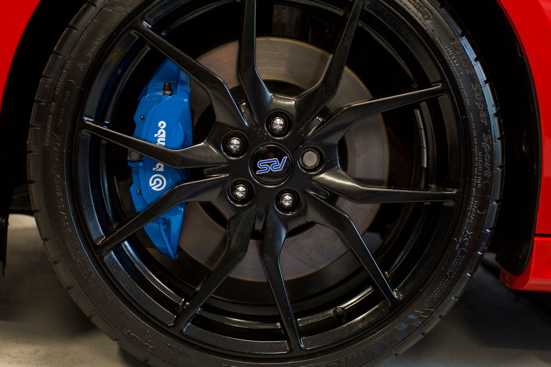 Black car wheel with blue Brembo brake caliper. | Plandome Service Center