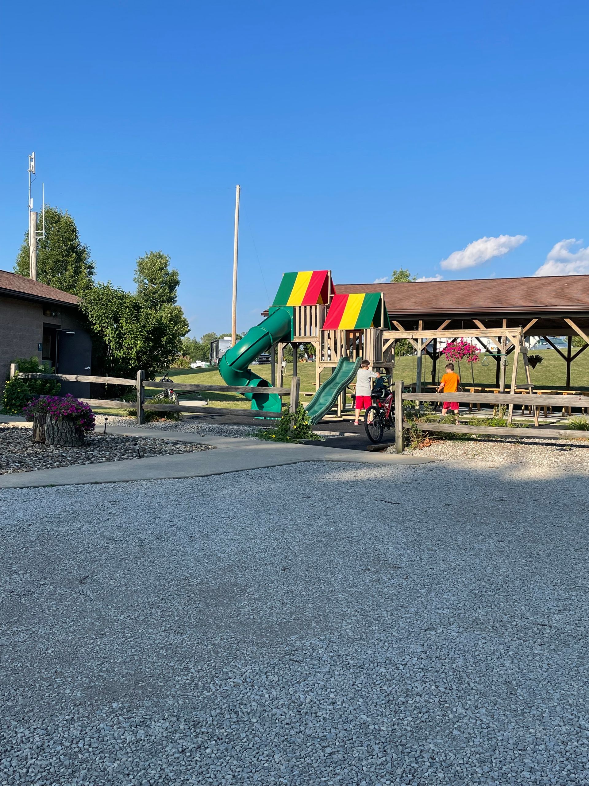 Playground with a slide, person in red shirt, blue sky.
