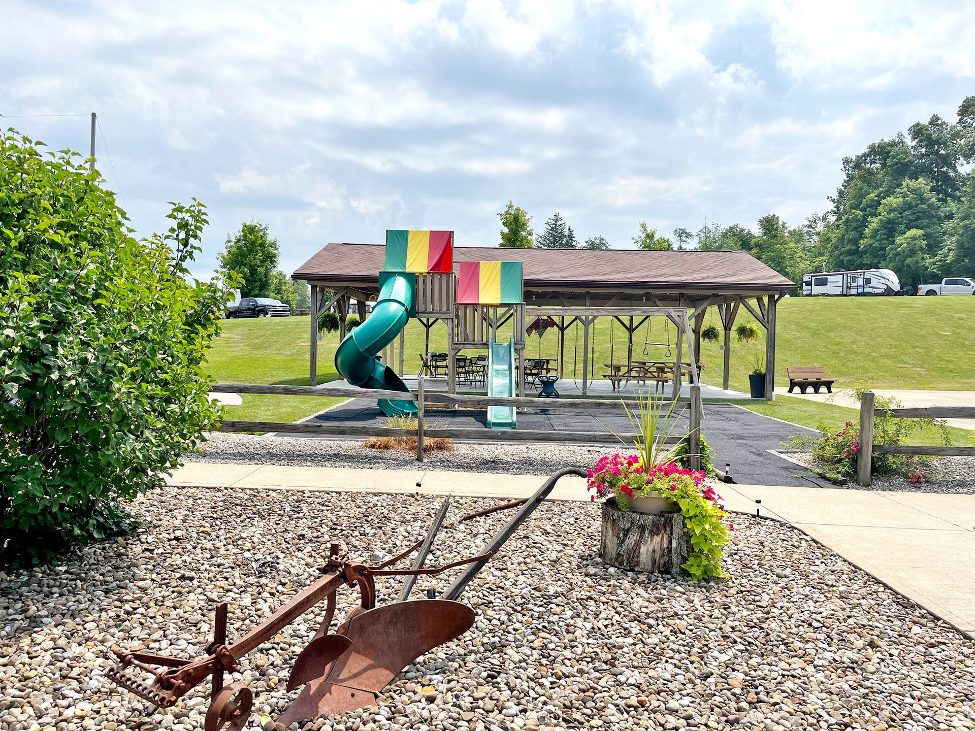 Park scene with playground, covered picnic area, and a decorative flower pot.