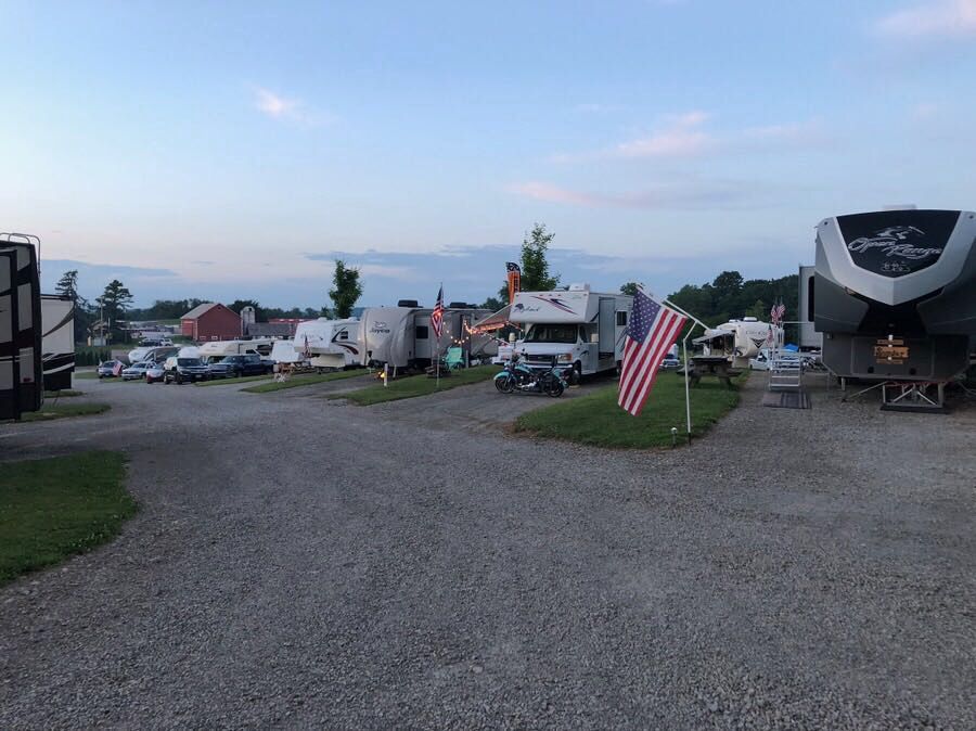 RV campground, gravel lots, American flag, multiple recreational vehicles, dusk sky.