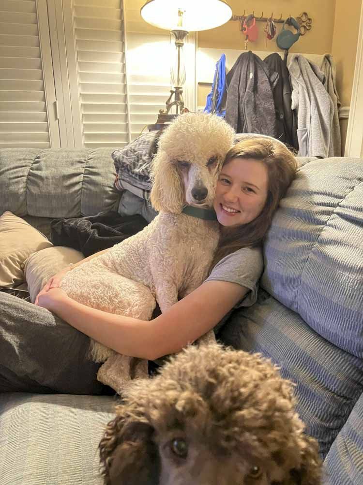 A woman is sitting on a couch with two dogs.