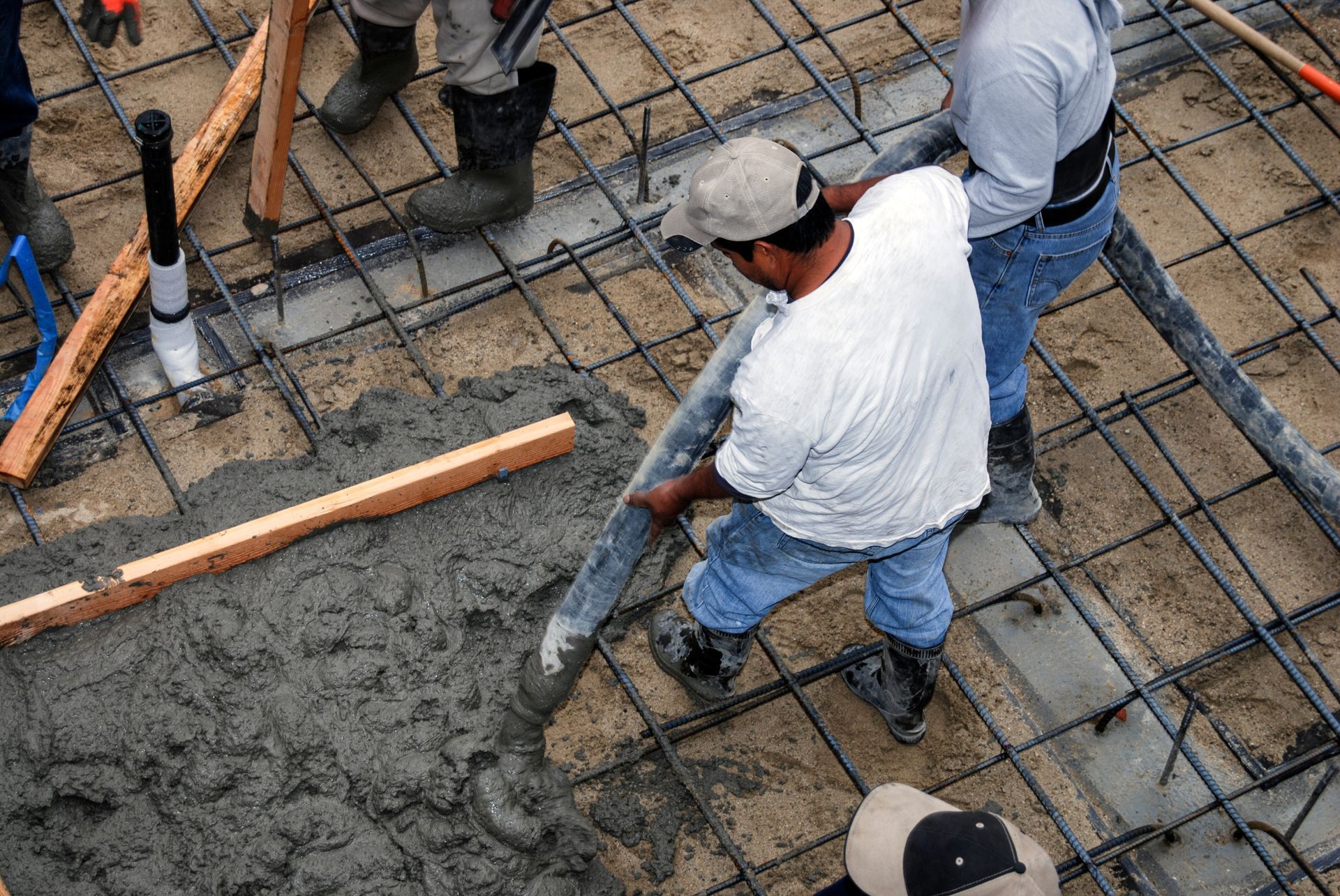 Concrete pumping services crew placing concrete through a hose onto a rebar slab.